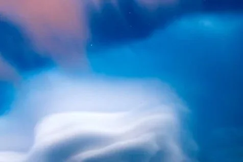 Abstract blue and white cloud-like formations in the sky.
