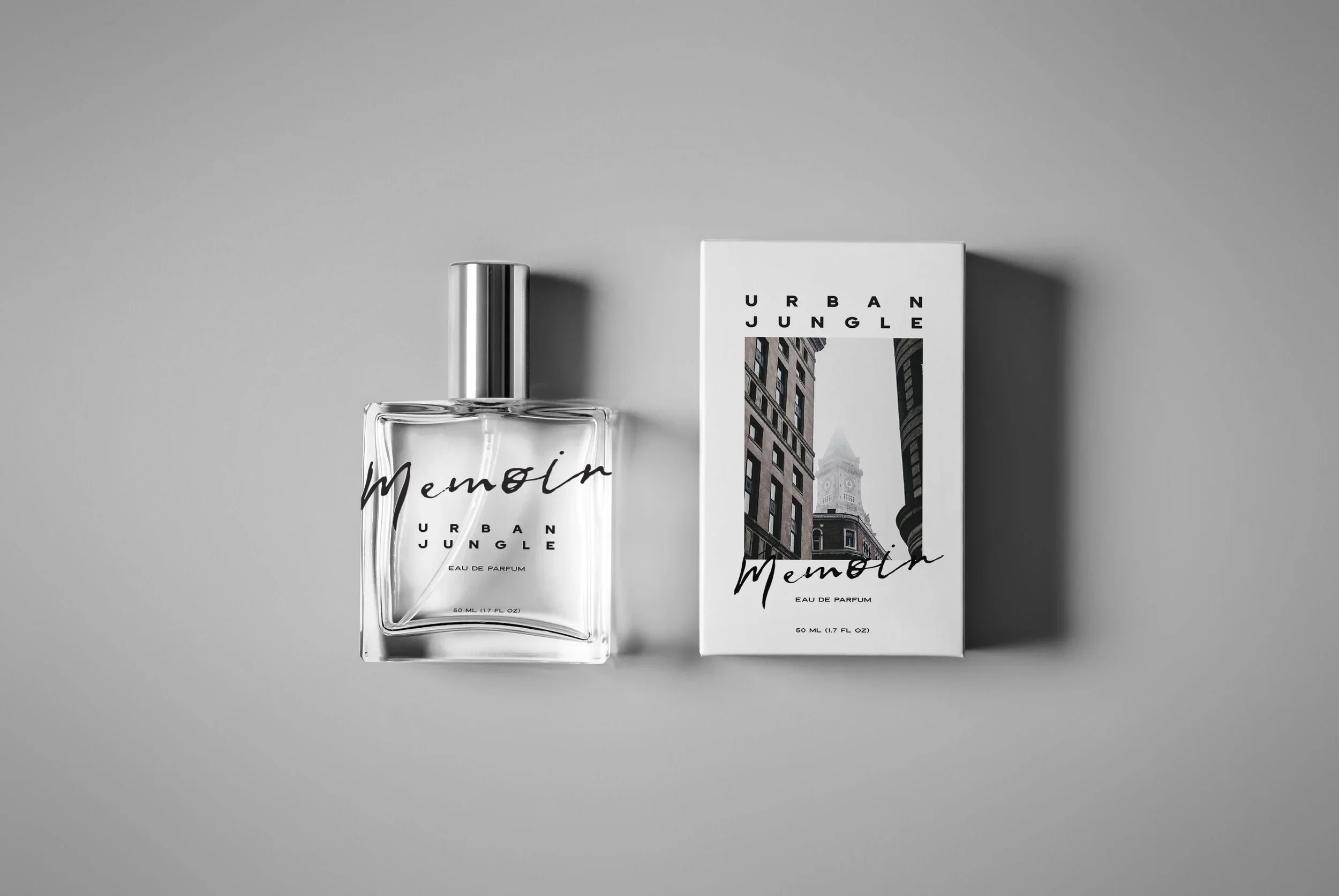 A perfume bottle and its box both labeled 'Urban Jungle Memoir Eau de Parfum' are displayed on a gray surface. The box features a black-and-white cityscape photograph with the Empire State Building visible.