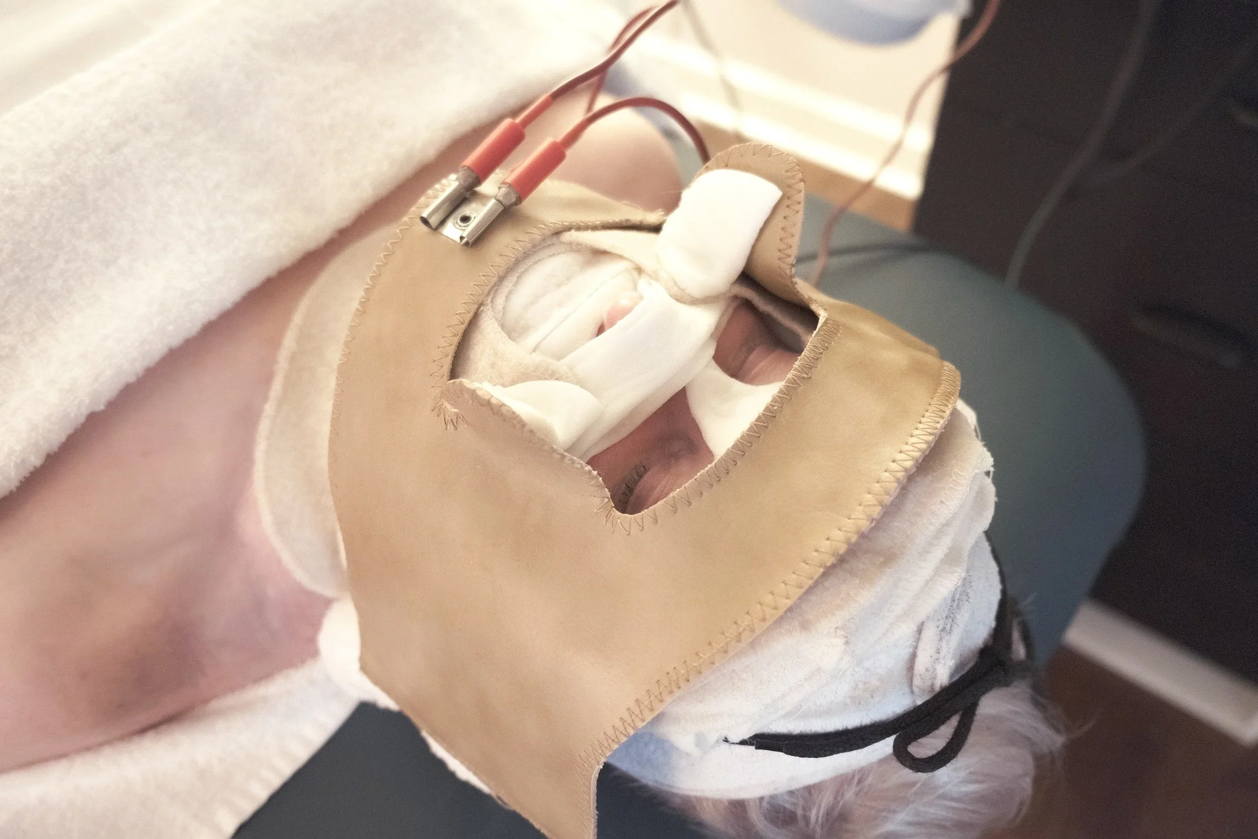 Close-up of a medical simulation or training mannequin with electrodes attached to the chest area, lying on a cloth surface.