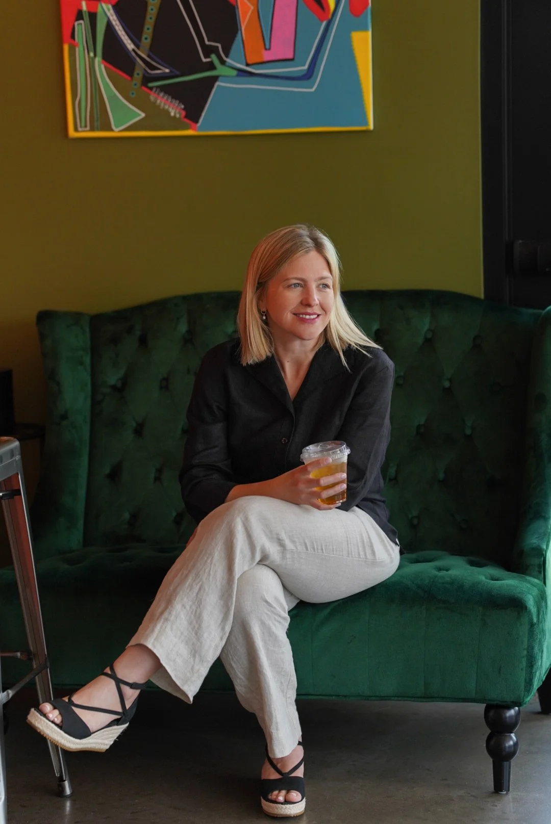 Chantelle sitting on a couch and smiling holding an iced tea