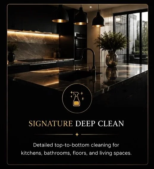 A modern kitchen with dark cabinets, a black marble island, and gold accents, featuring pendant lights and large windows, promoting a deep clean service.