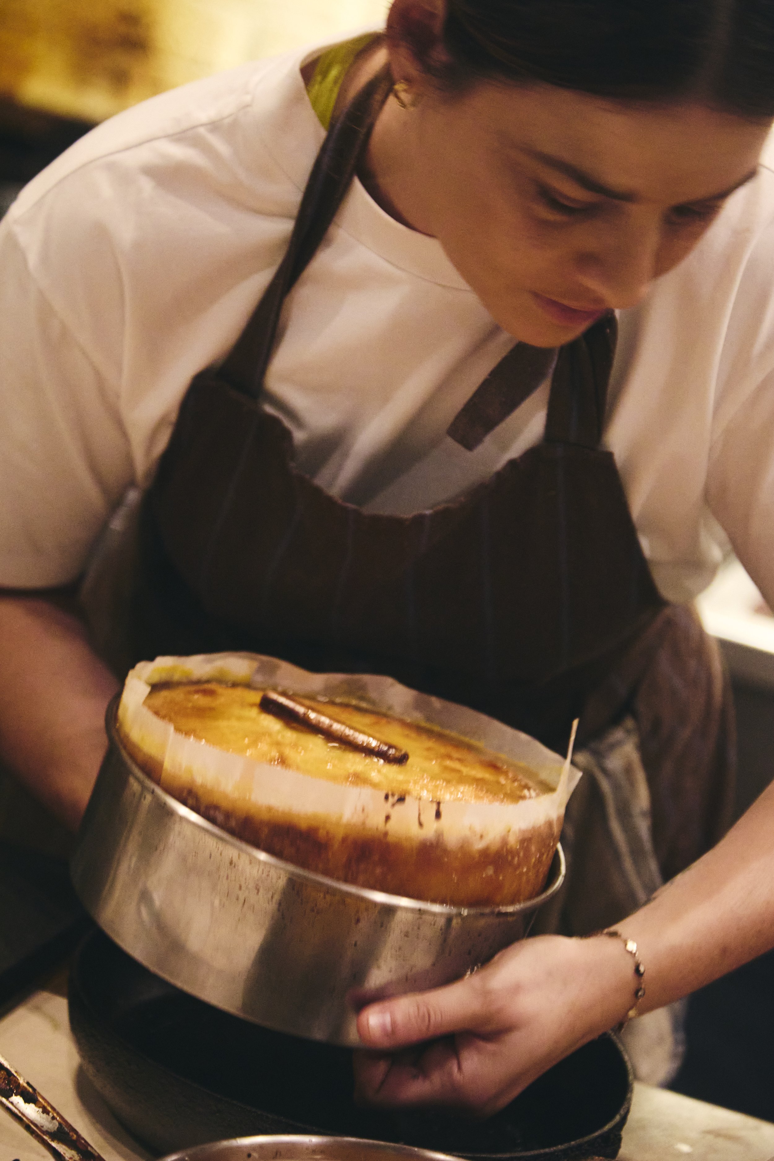 A person holding a large container of crème brûlée topped with caramel and chocolate.