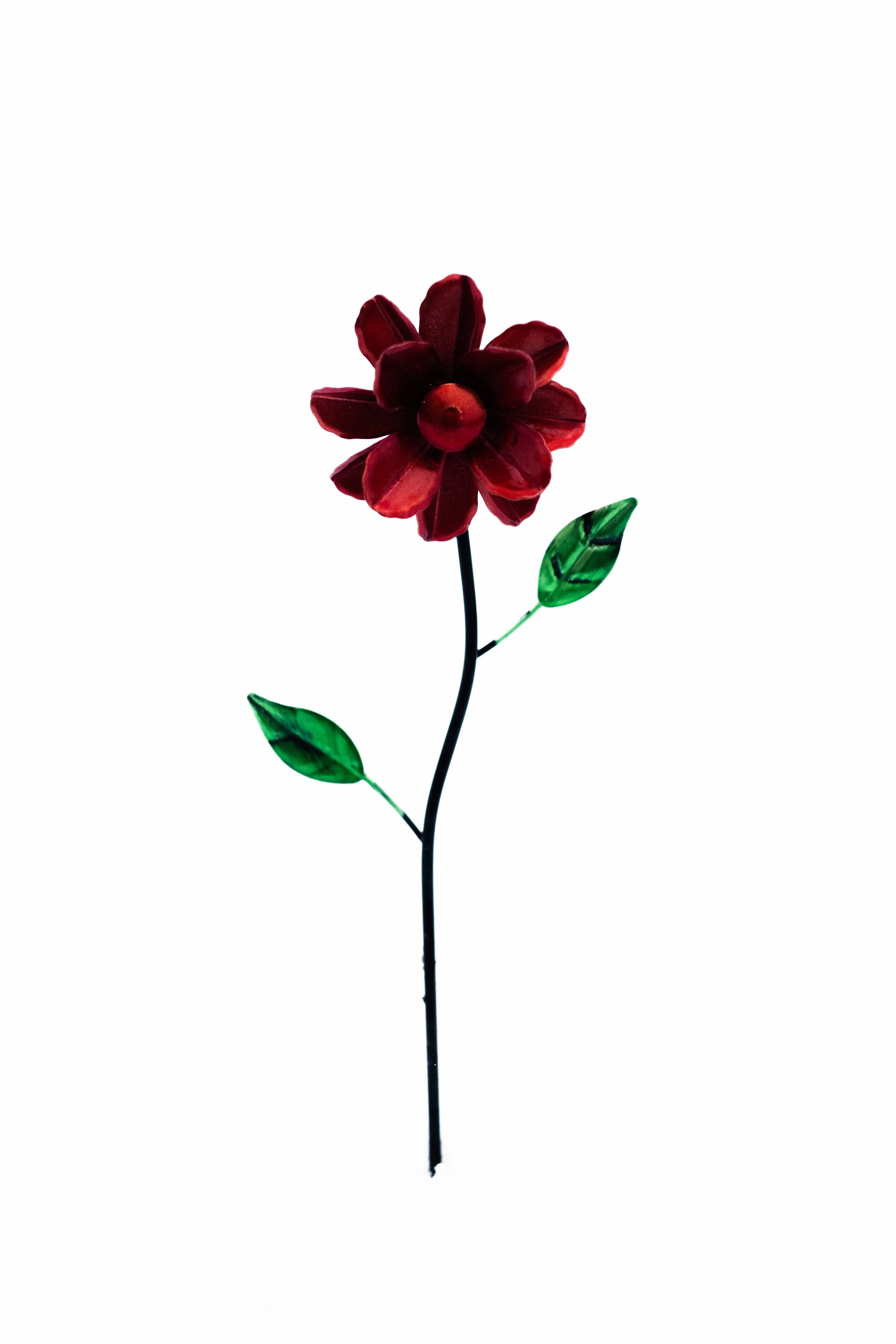 Artificial flower with red petals, green leaves, and a black stem, set against a white background.