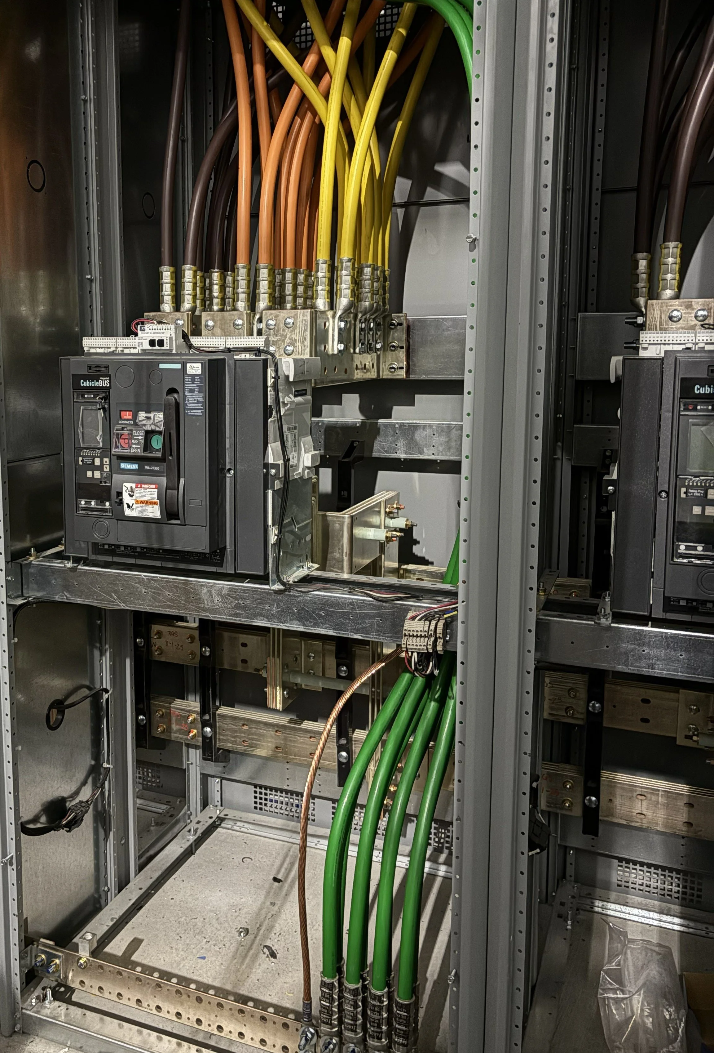 Inside an electrical control panel with green, yellow, orange, and brown wires connected to various components.