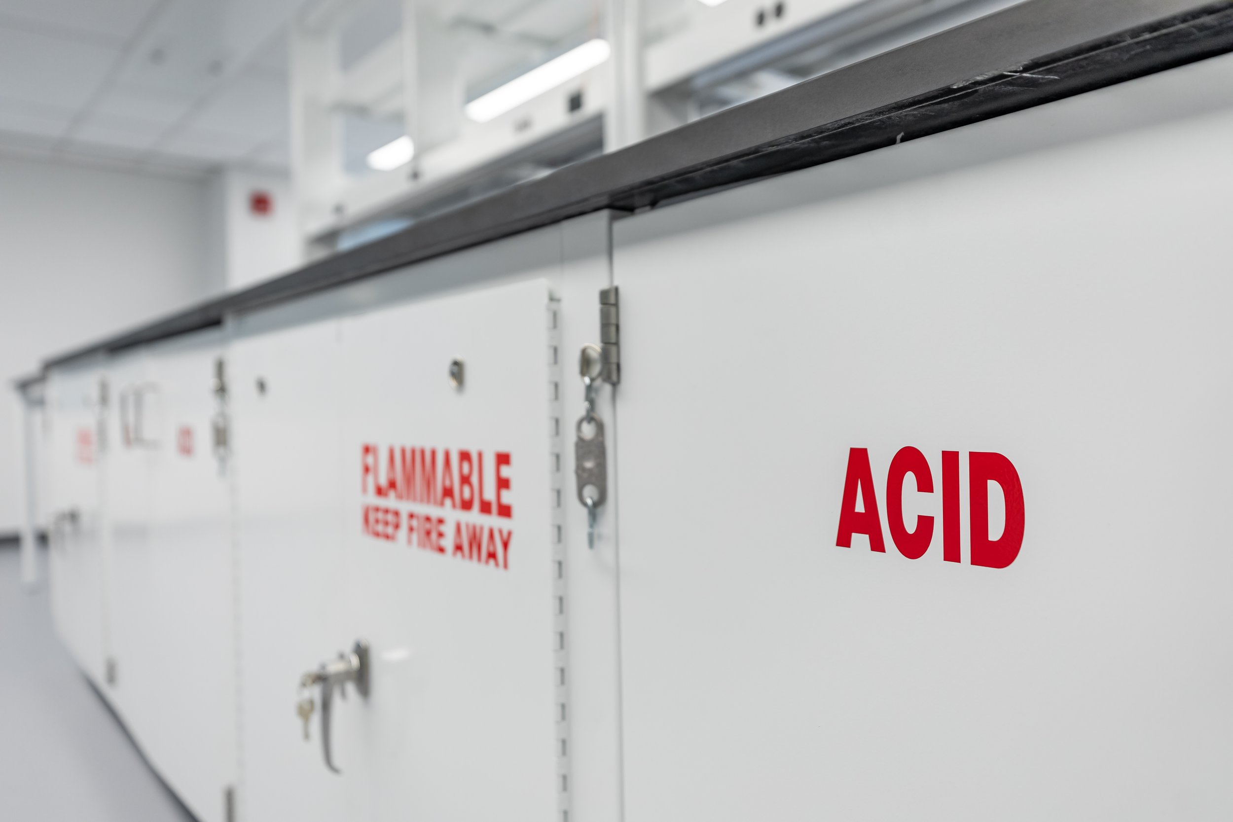 White emergency cabinet with red 'FLAMMABLE' and 'KEEP FIRE AWAY' warning labels, and silver lock and latch mechanism.