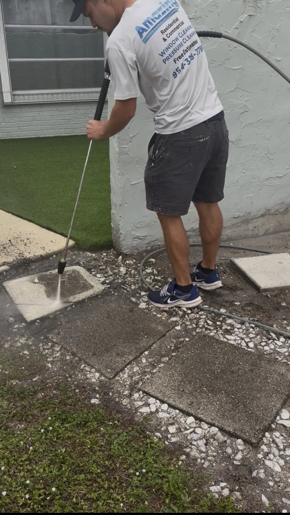 Professional pressure washing of a concrete driveway and walkway in South Florida.