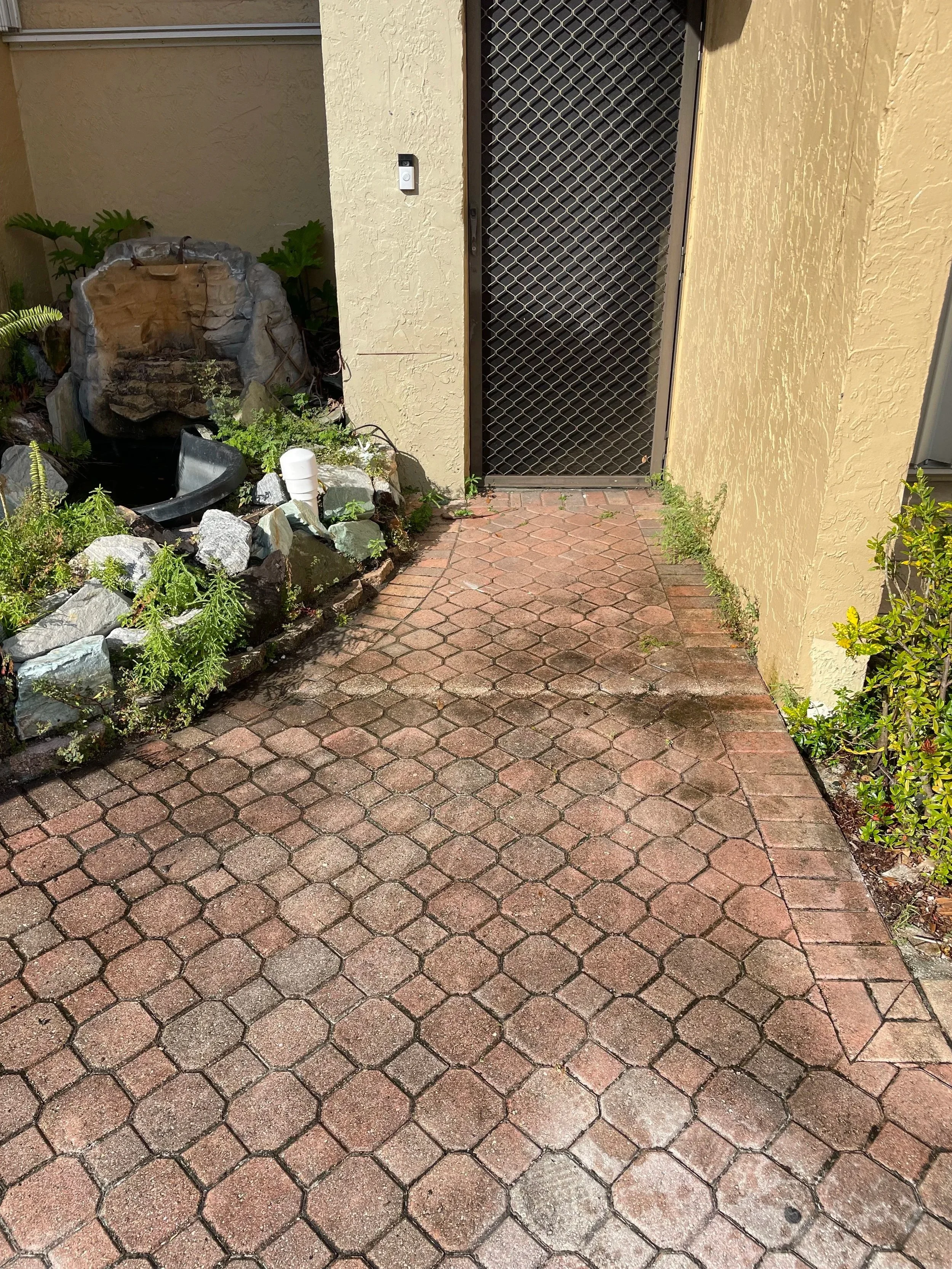 Before pressure washing showing a dirty brick paver front entrance.