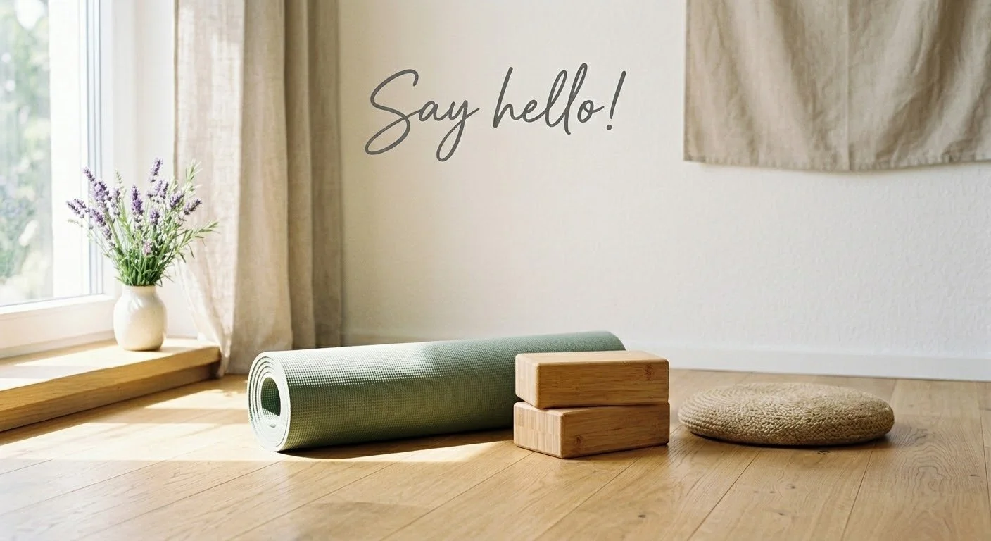 Yoga mat rolled on the floor next to wooden blocks and a round cushion, with a vase of purple flowers on the windowsill in a room with sunlight.