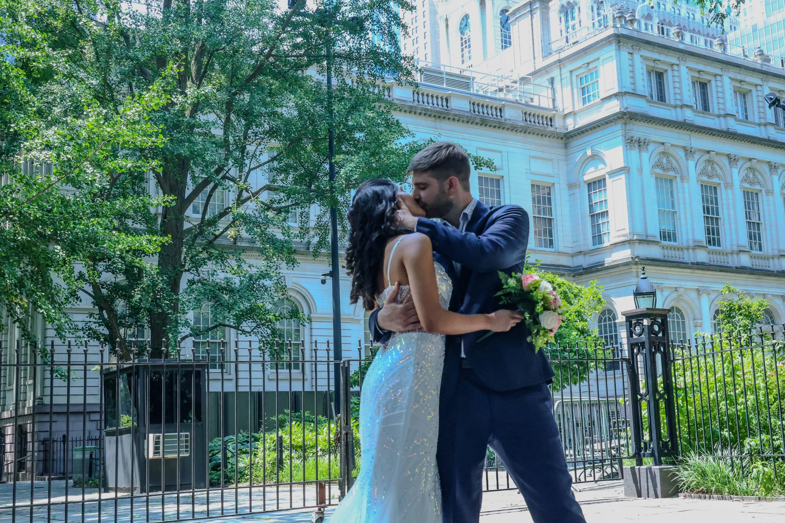 Bride and groom kissing during an outdoor wedding portrait session near historic architecture in NYC