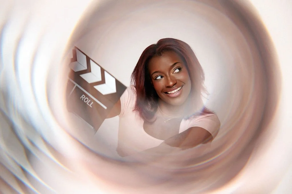 A woman with brown hair holding a film clap board with a calydiscope filter.