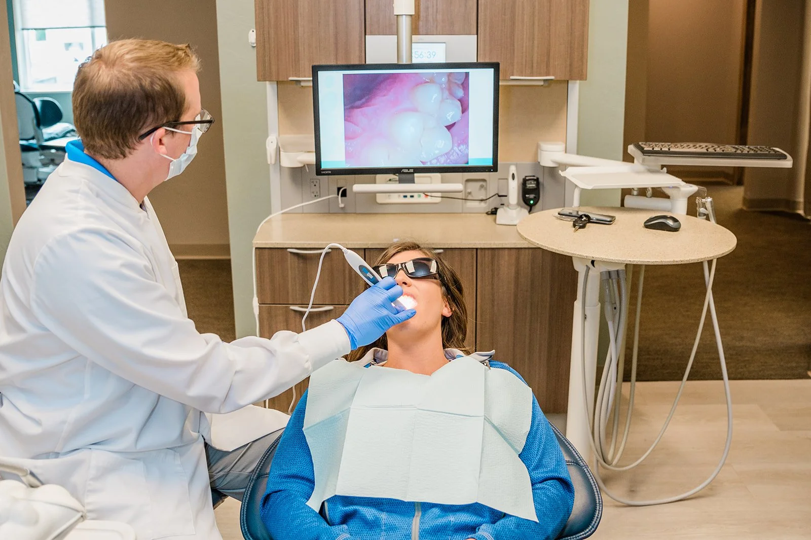 Dentist using a dental curing light on a patient's teeth in a dental office.
