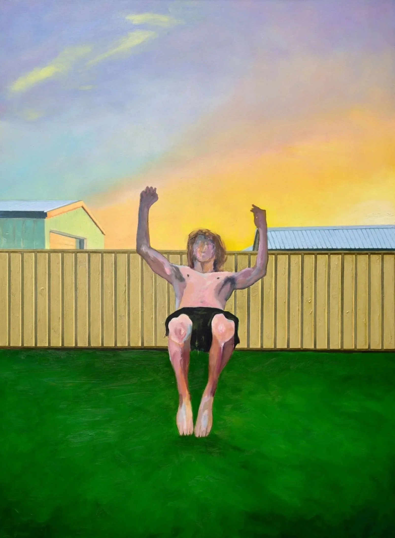 A person with light skin and blond hair performing a backflip in a yard, with a yellow fence in the background, during sunset, with their arms raised mid-flip and wearing shorts.
