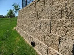 A stone wall with a grassy area and trees in the background.