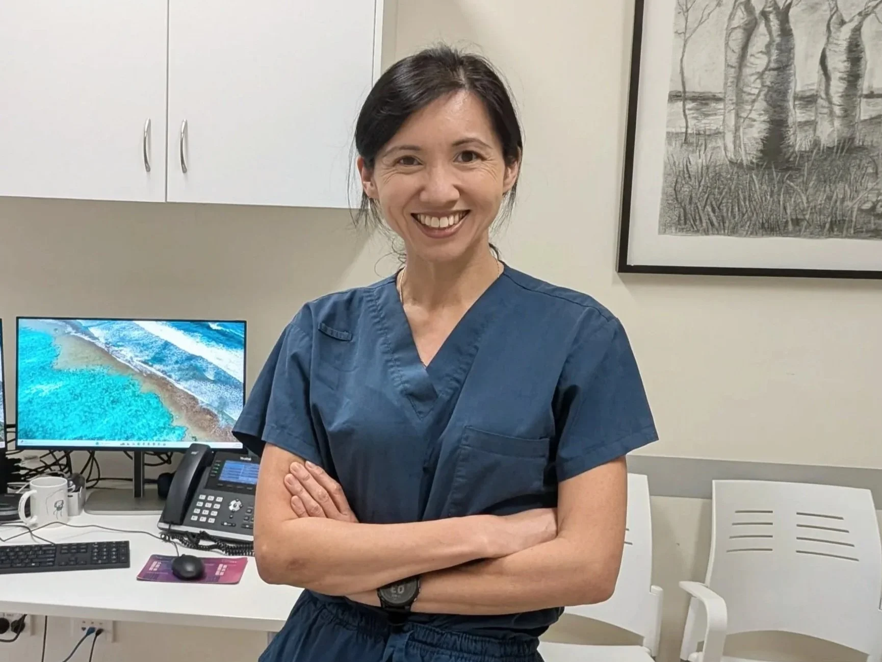 Dr Charissa Ho, a general practice, women's health and family medicine doctor, stands in front of the desk in her clinic room.