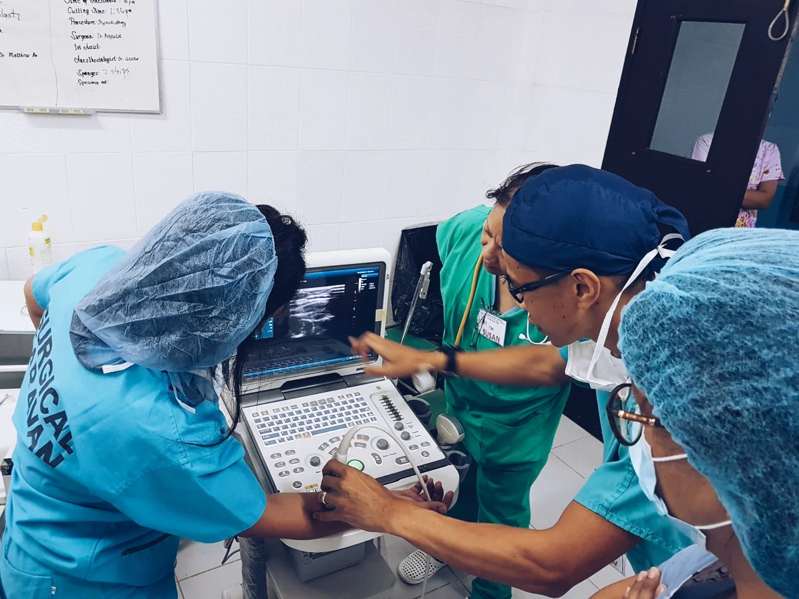 Dr Matthew Ho, specialist anaesthetist, and healthcare professionals examining an ultrasound image on a monitor in a clinical setting.