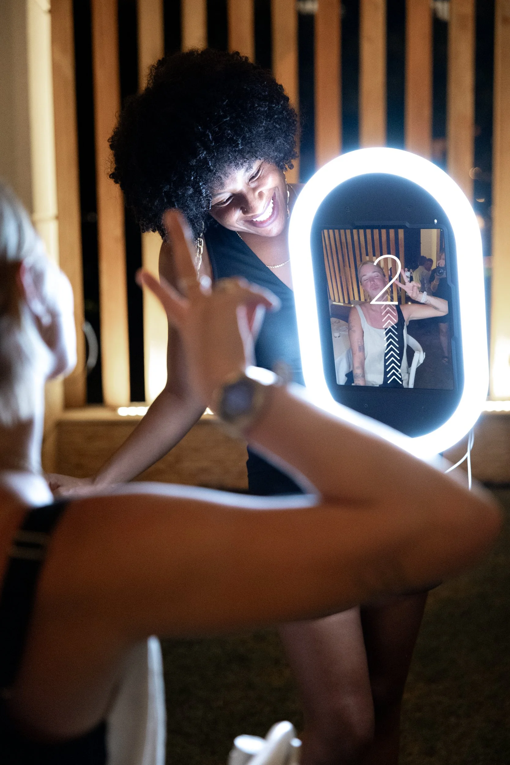 A guest posing at The 1881 Studio photo booth in front of a ring light and wood-panel backdrop.