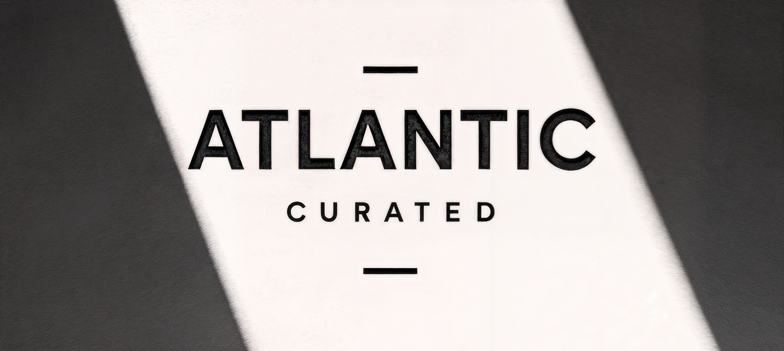 Close-up of a graphic design with the words 'Atlantic Curated' in bold black letters against a black and white background.