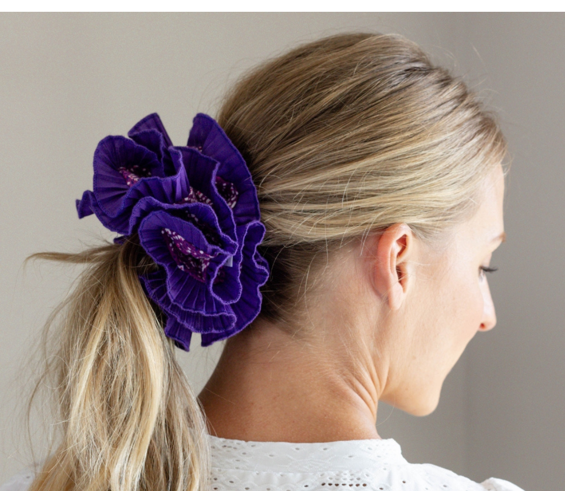 Side view of a woman with blonde hair wearing a large purple ruffled scrunchie by Birdcraft Studio, handmade from reclaimed fabric.