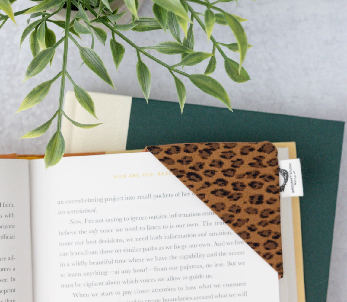 Animal-print fabric corner bookmark by Birdcraft Studio, handmade from reclaimed textile and styled in an open book.