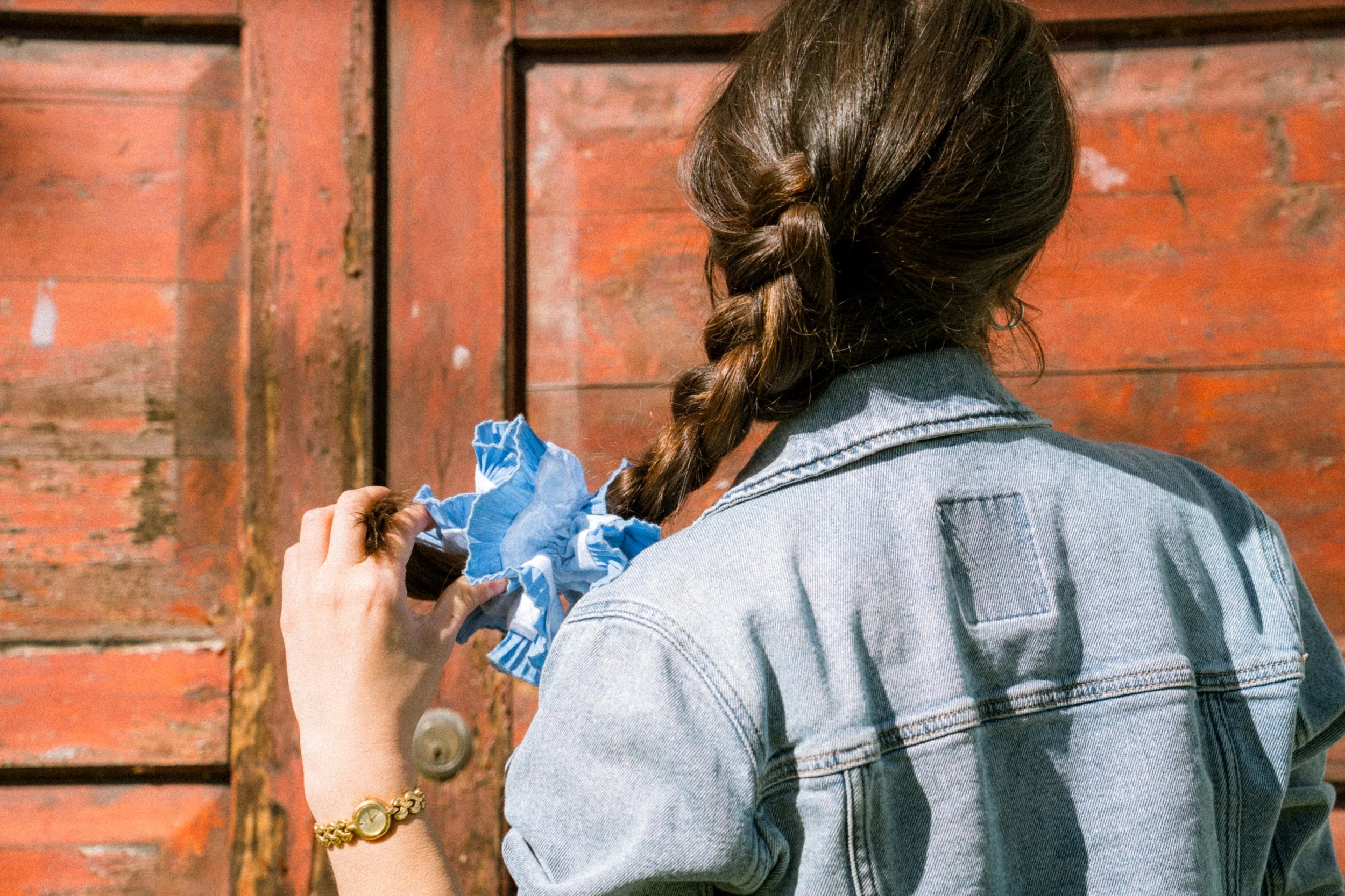 Woman with braided brown hair wearing a blue Birdcraft Studio ruffled scrunchie made from reclaimed fabric.