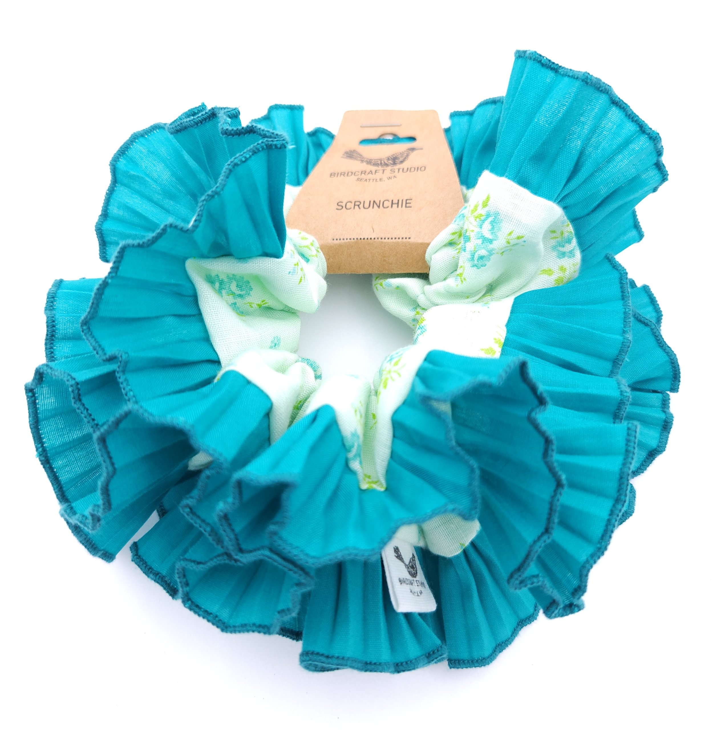 Blue teal upcycled fabric scrunchie with a ruffled design and Birdcraft Studio label.