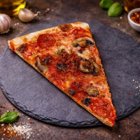 Slice of pepperoni and mushroom pizza on a black slate platter
