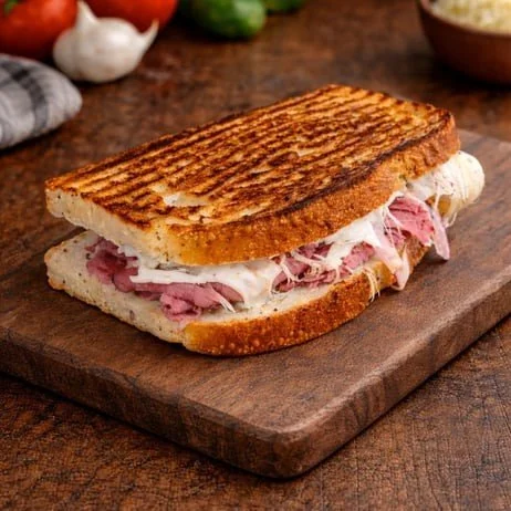Grilled ham and cheese sandwich on a wooden cutting board.