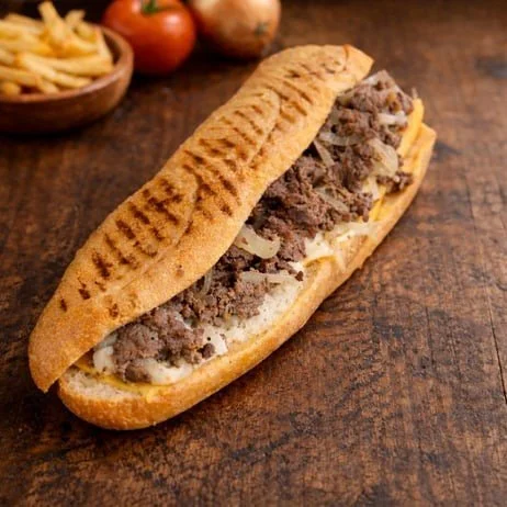 Philly cheesesteak sandwich with beef, melted cheese, on a toasted hoagie roll.