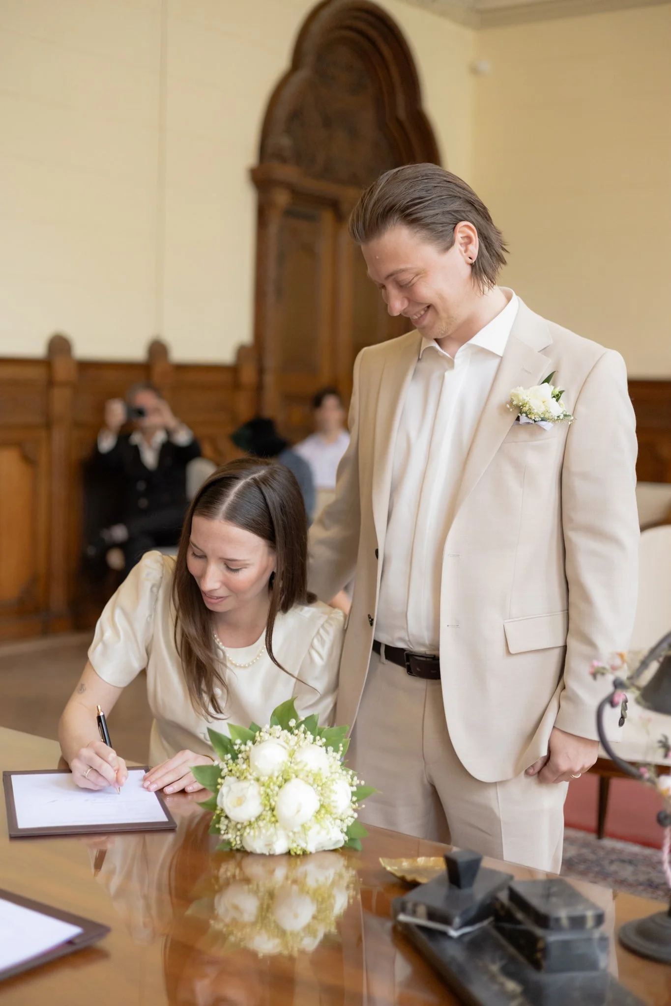 Ein Paar bei einer Hochzeitszeremonie, das Braut und Bräutigam beim Unterschreiben ihrer Heiratsurkunde zeigt.