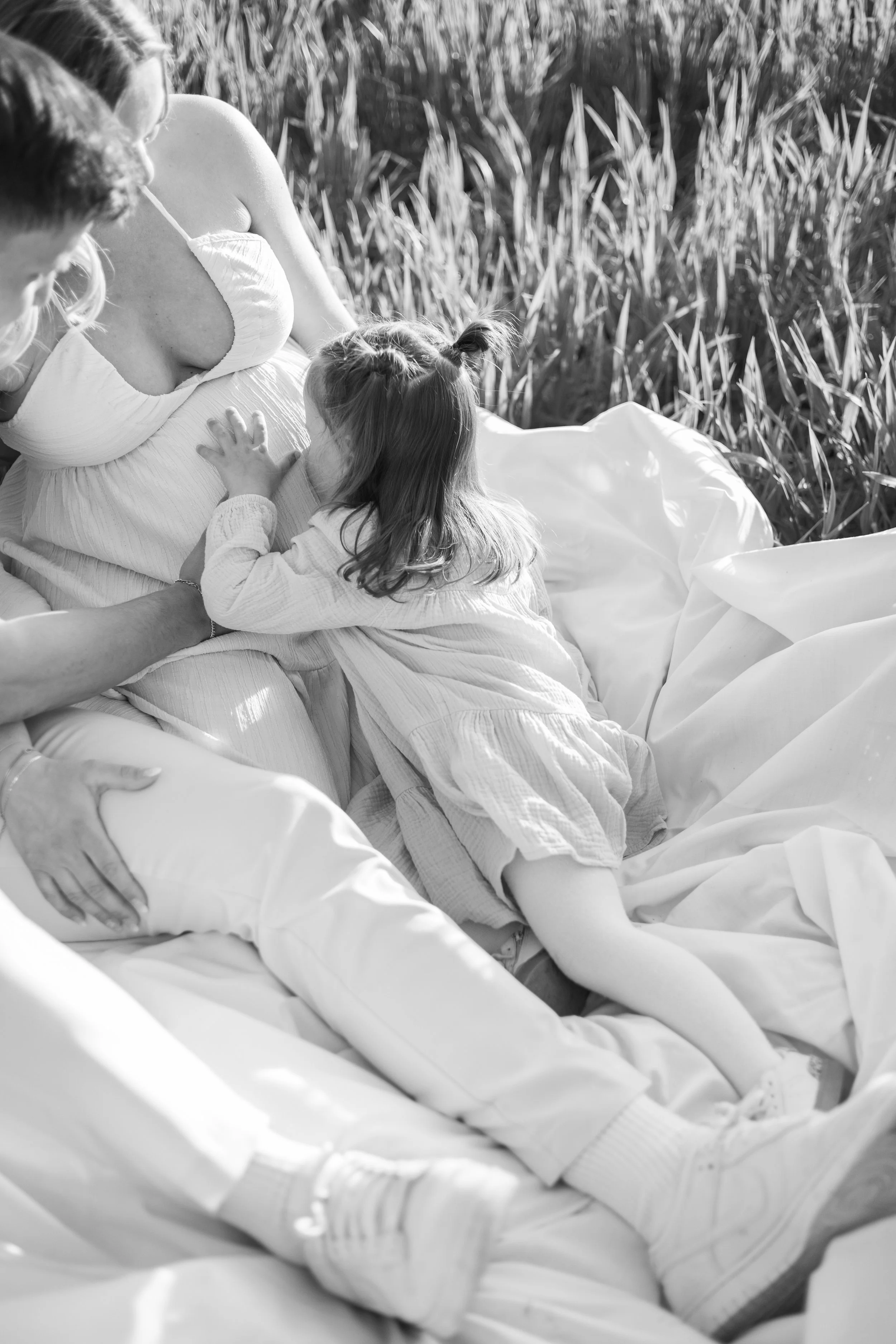 Kinder und Frauen in einer natürlichen Umgebung mit Körnerpflanzen, wahrscheinlich in einem Feld, in Schwarz-Weiß-Fotoaufnahme.