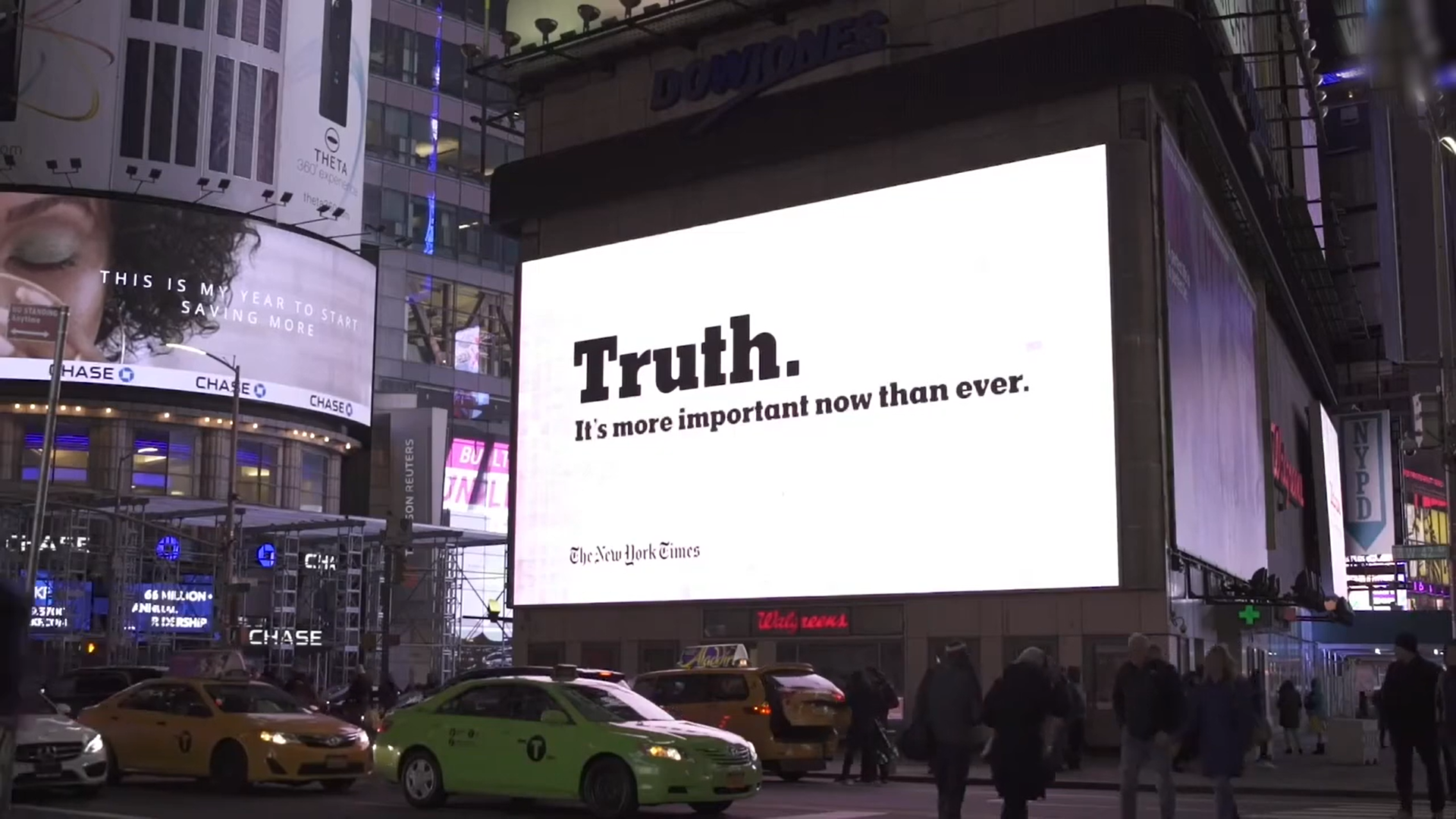 Large illuminated billboard displays the message "Truth. It's more important now than ever." with attribution to The New York Times. The scene is set in Times Square at night with people on the street, taxis, and surrounding advertisements.