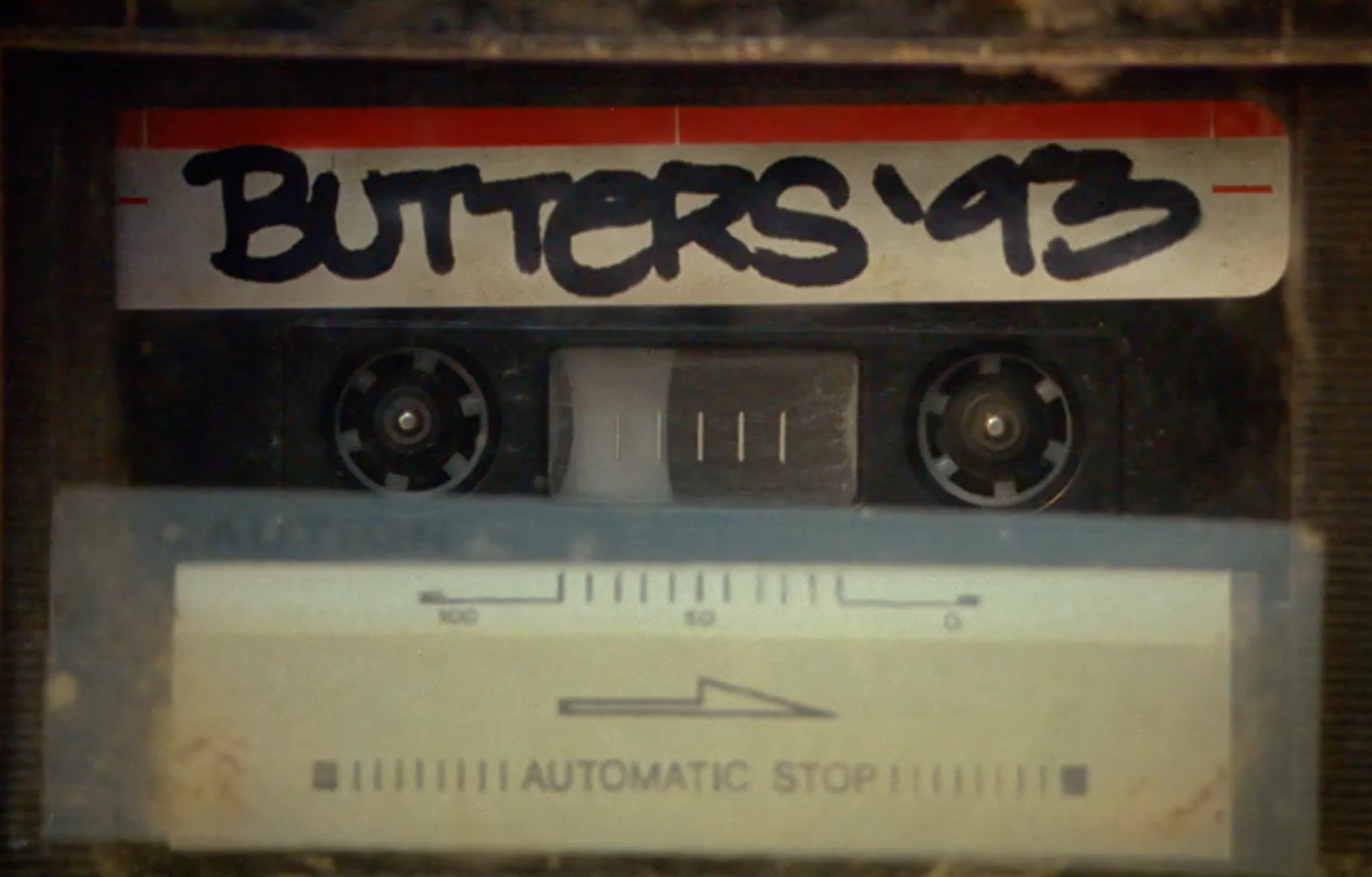 A vintage cassette tape labeled 'BUTTERSS' and a portion of an automatic stop cassette player.