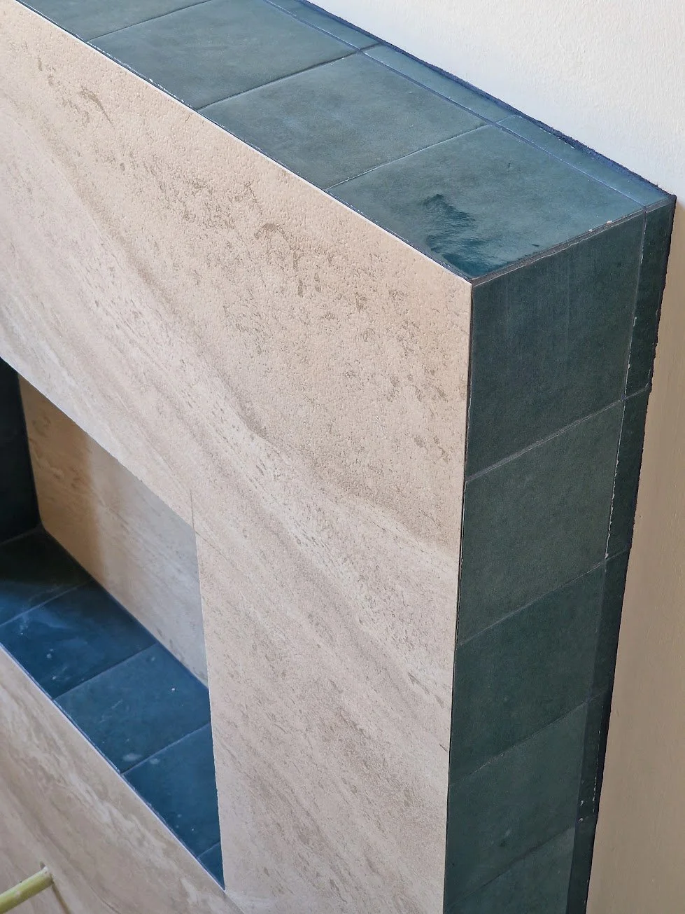 Una struttura in pietra con un'apertura a forma di rettangolo e rivestimenti di piastrelle verdi sopra e ai lati.
