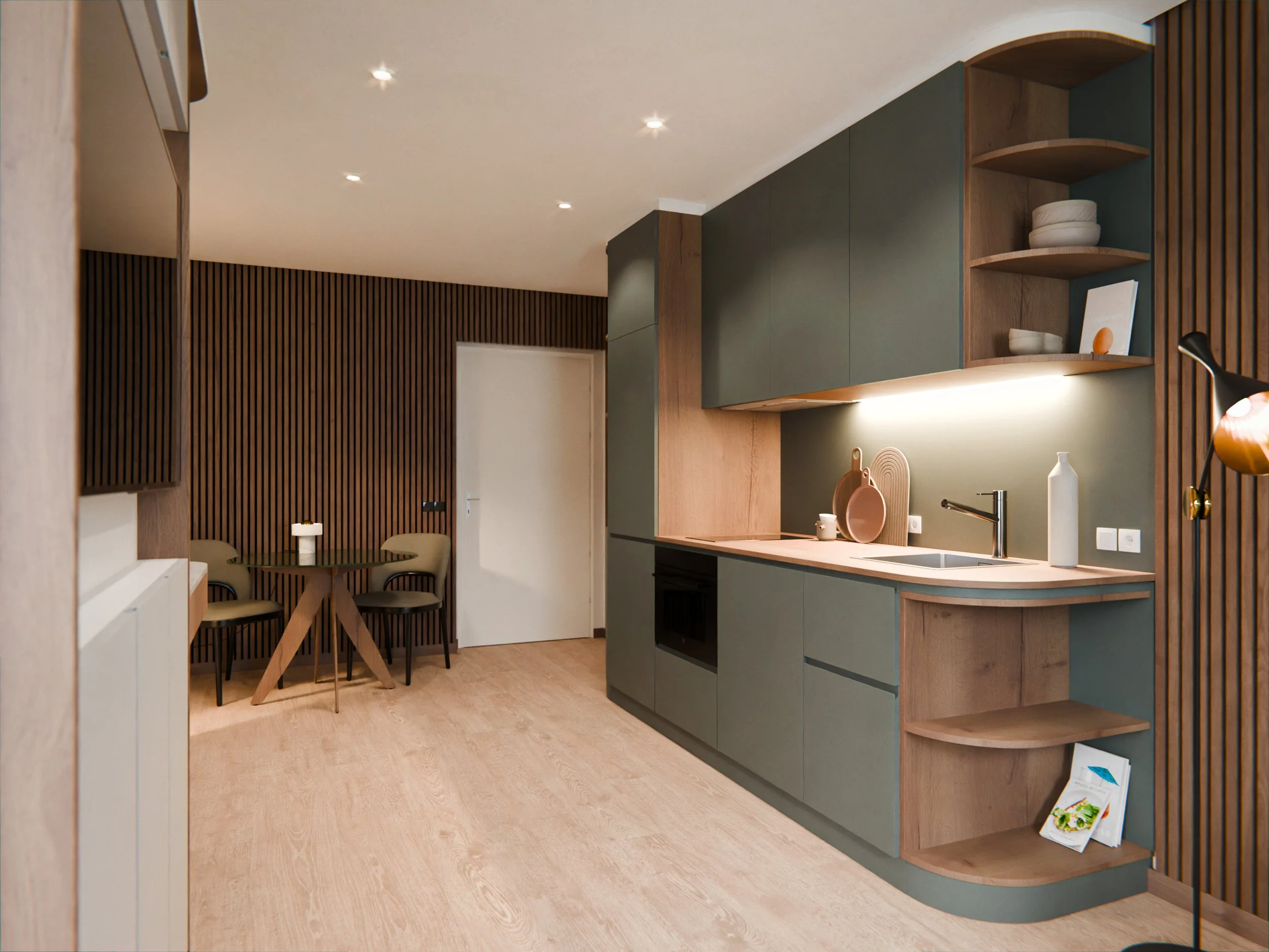 Interno di una cucina moderna con mobili verdi, pareti in legno e scaffali con oggetti decorativi. Zona pranzo con tavolo rotondo e sedie