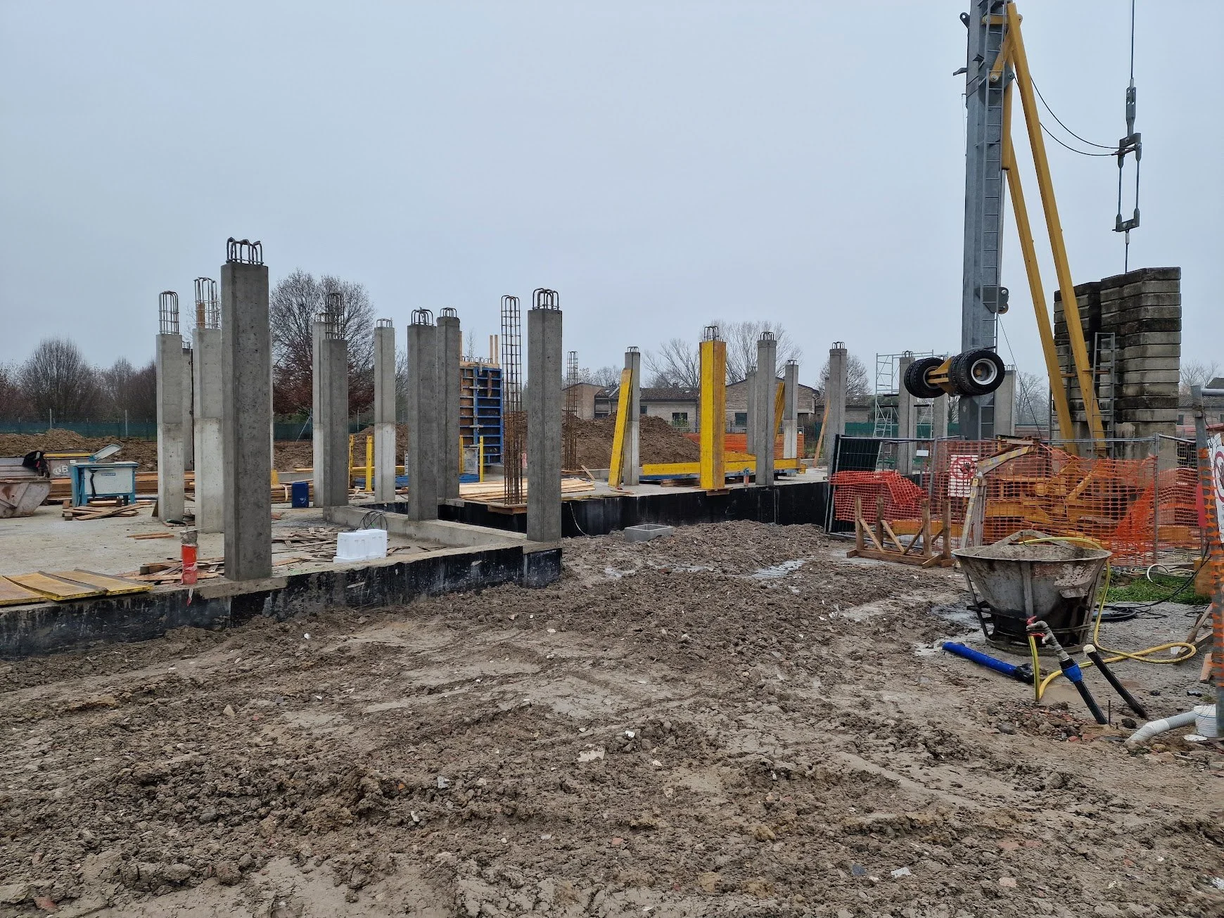 Cantiere edile con pilastri in cemento, gru e attrezzature da costruzione in un'area all'aperto