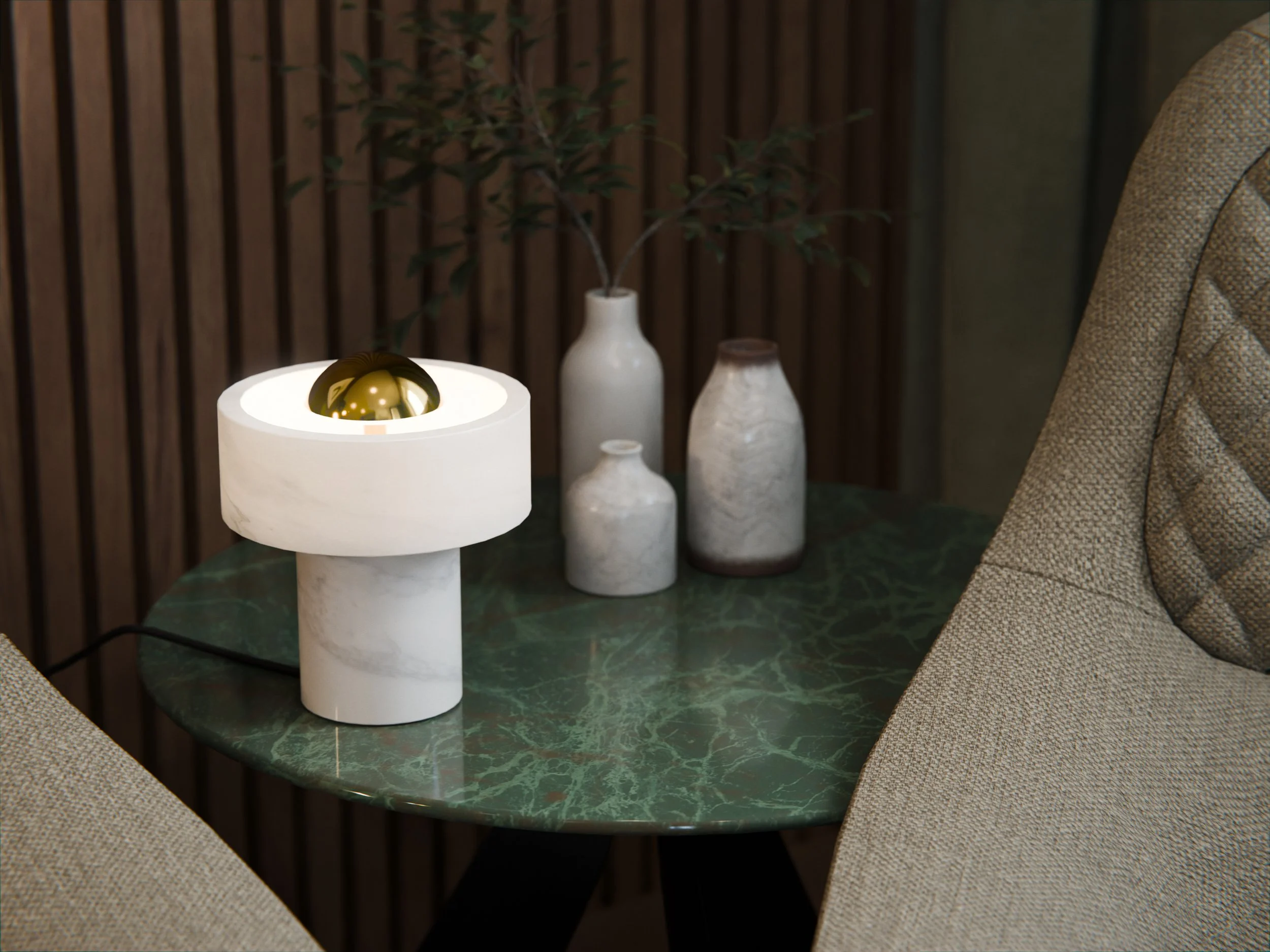 Lampada da tavolo bianca con finitura in oro, posizionata su un tavolo in marmo verde, con vasi in ceramica e una pianta sullo sfondo in un ambiente decorato con pannelli di legno.