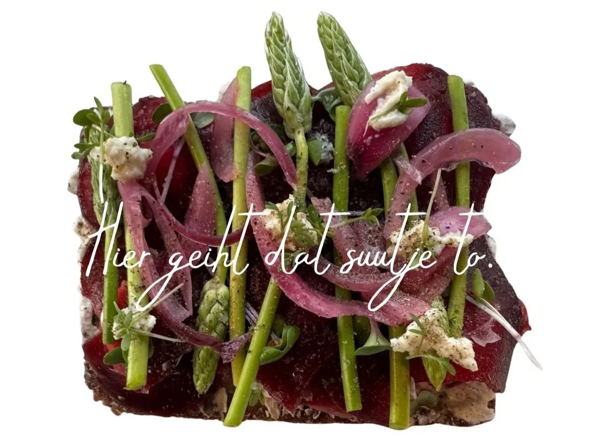 Smørrebrød „Wilde Beete“ mit Beilagensalat
lokaler Dattel-Walnuss Frischkäse · rote Beete · wilder Spargel · 
eingelegte Zwiebeln · Meerrettich. Darauf steht der Schriftzug "Hier geiht dat suutje to."