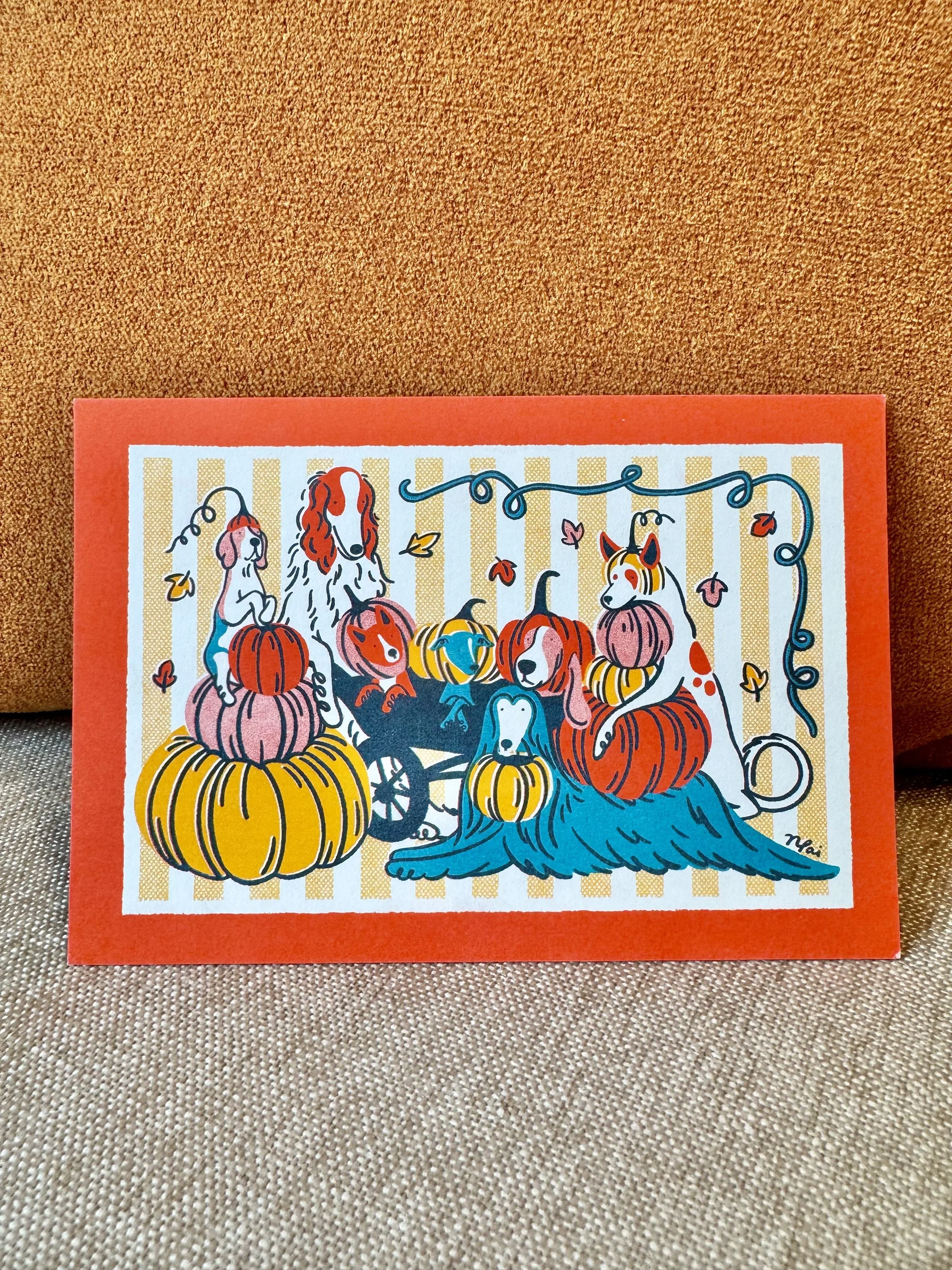 Colorful illustration of dogs and pumpkins with a Halloween theme, with a striped orange background and bright orange border.