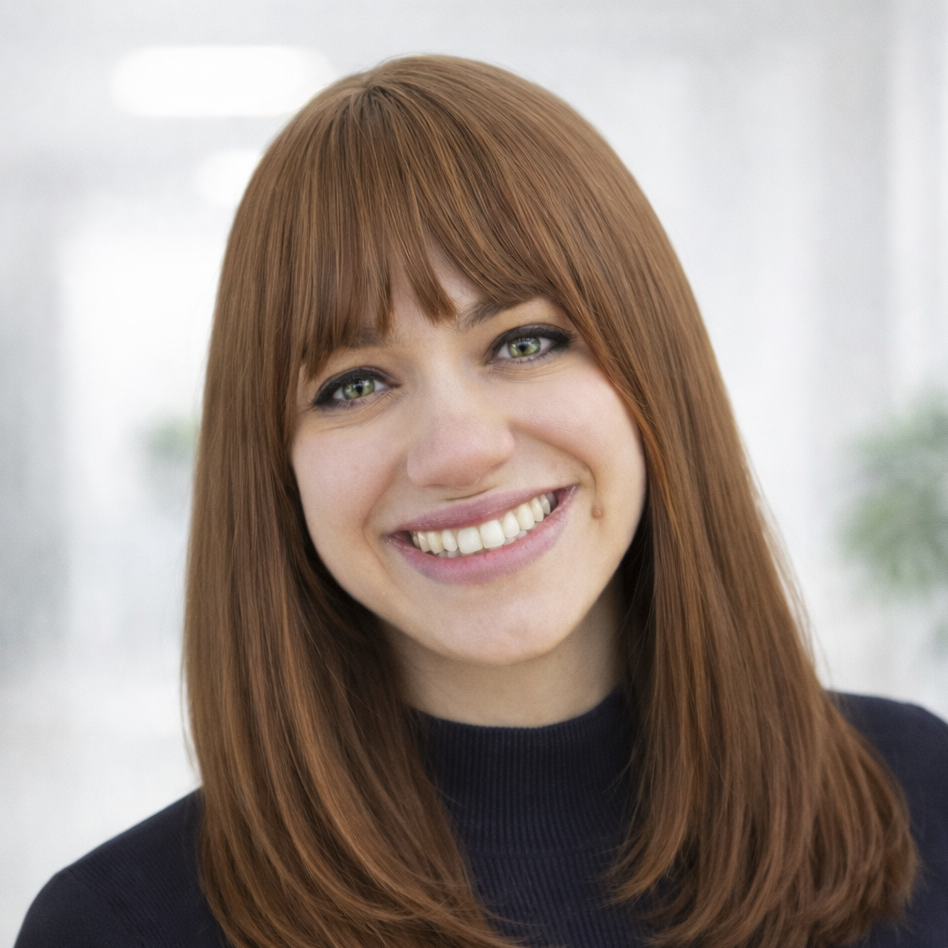 Close-up of a young woman with straight, shoulder-length red hair and green eyes, smiling and wearing a dark top, in a bright, blurred background. the mental health admin lead in our adhd, autism and general psychiatry team.