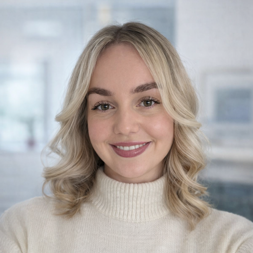 Close-up portrait of a young woman with blonde hair, smiling, wearing a cream-colored turtleneck sweater, in a bright indoor setting. a mental health medical secretary in our adhd, autism and general psychiatry team.