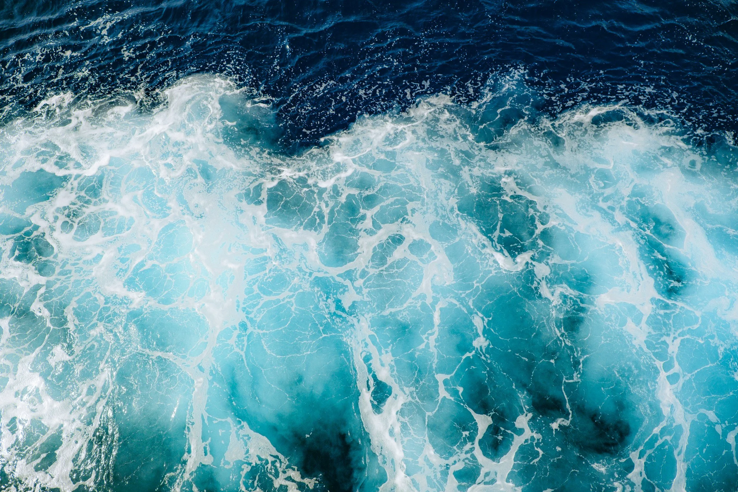 Aerial view of ocean waves with white foam and deep blue water