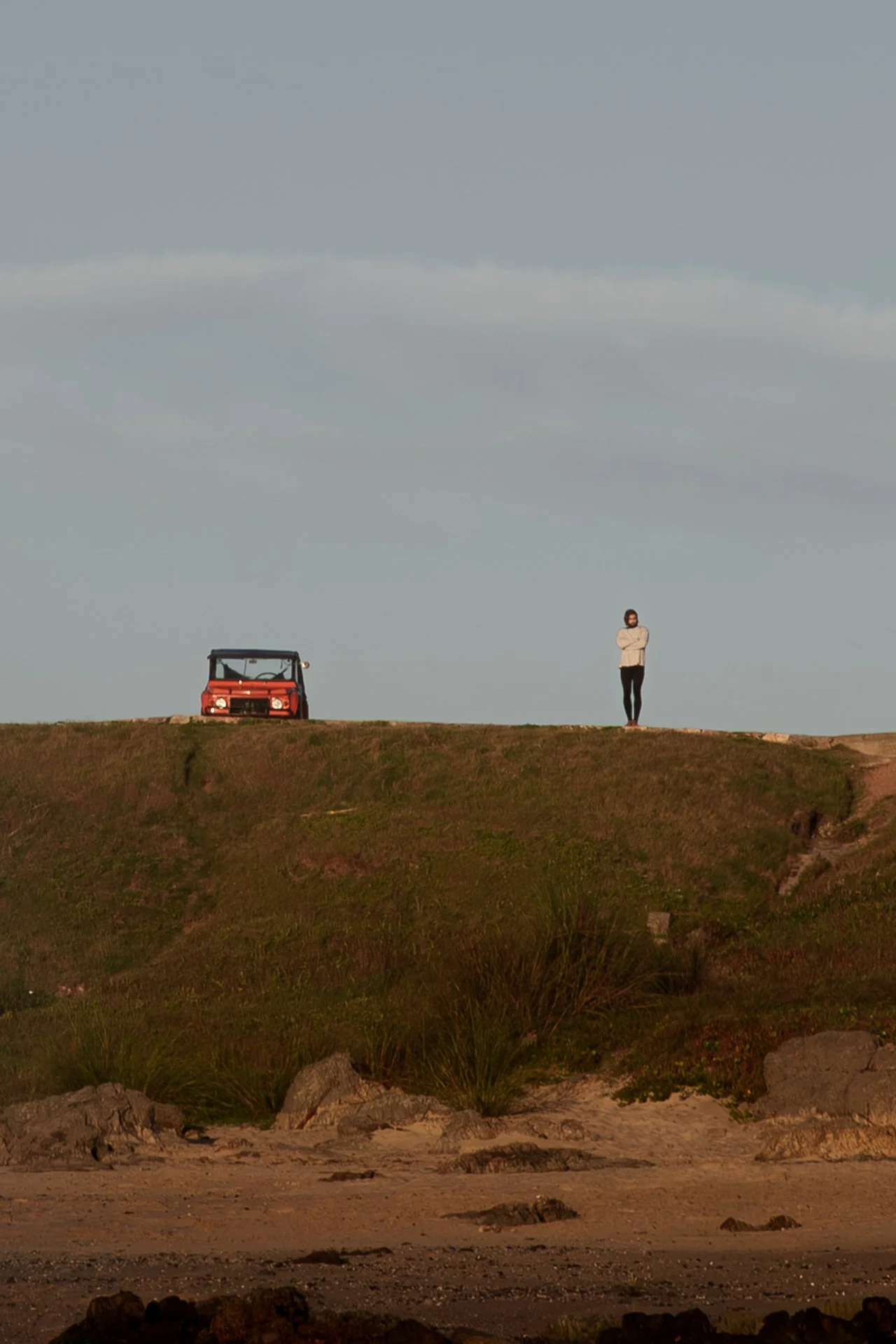 Solitary figure standing on a coastal headland overlooking the ocean.