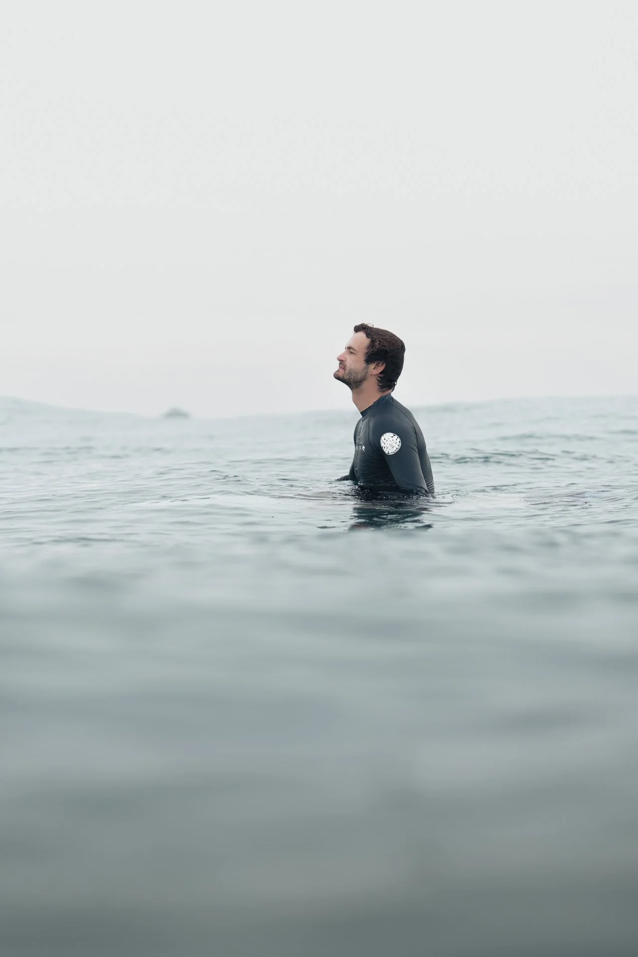 Surfer sitting quietly in the ocean in the line up, waiting for a wave. 