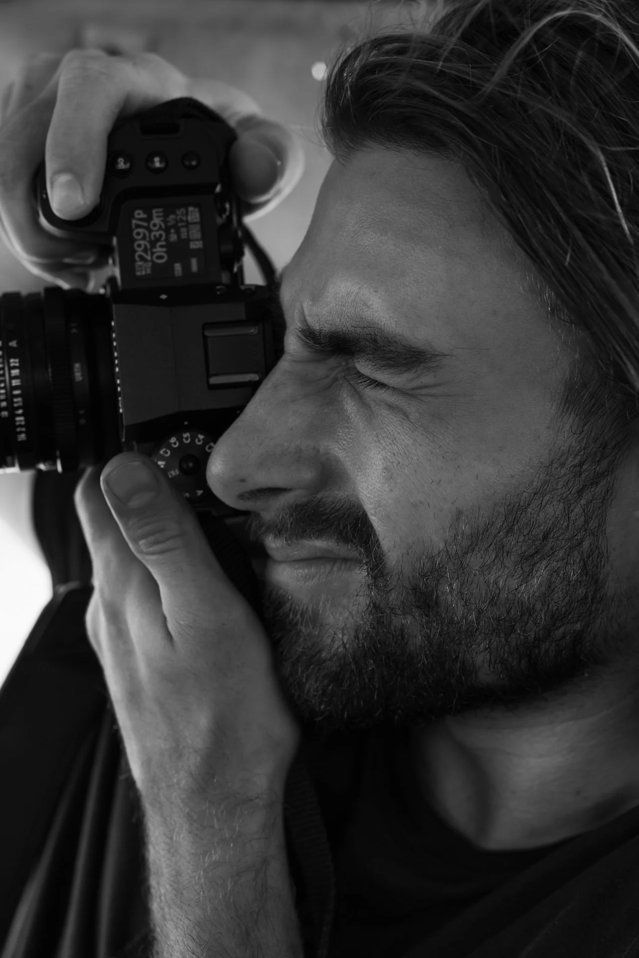 Editorial portrait of a photographer looking through a camera viewfinder.