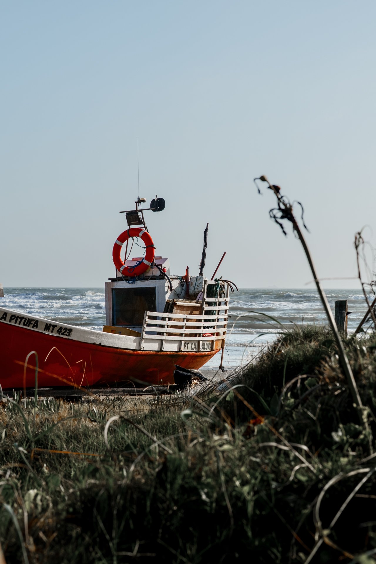 Small fishing boat resting on a remote shoreline beside the ocean.