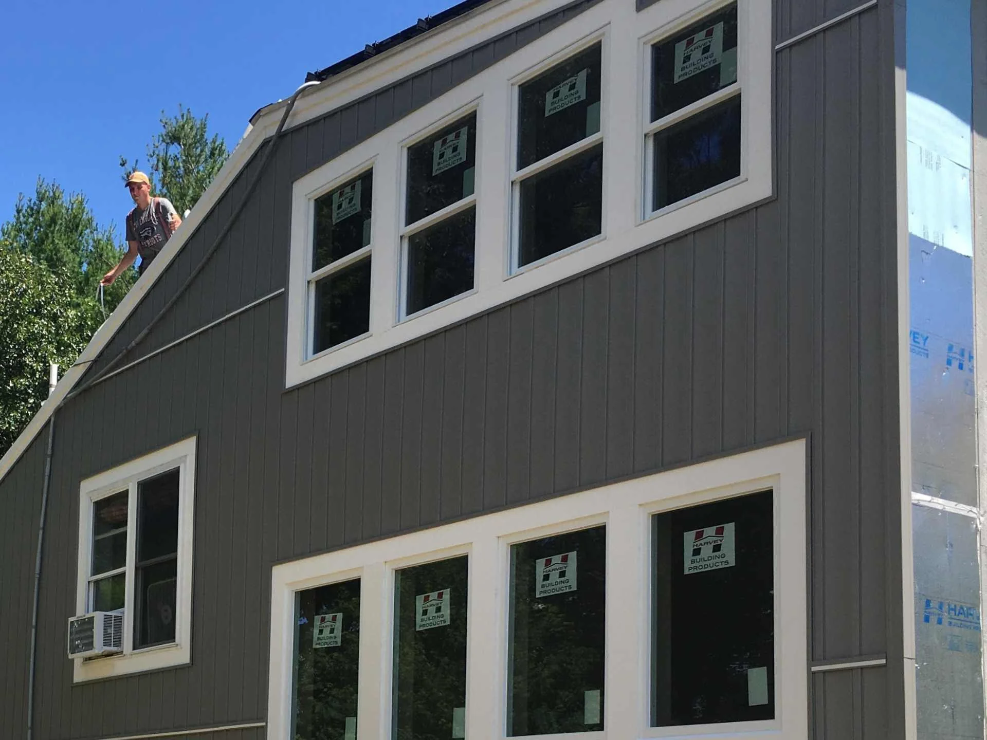 Exterior renovation of an existing house with grey siding, multiple rectangular windows, and an air conditioning unit in the lower left in Fitchburg, MA