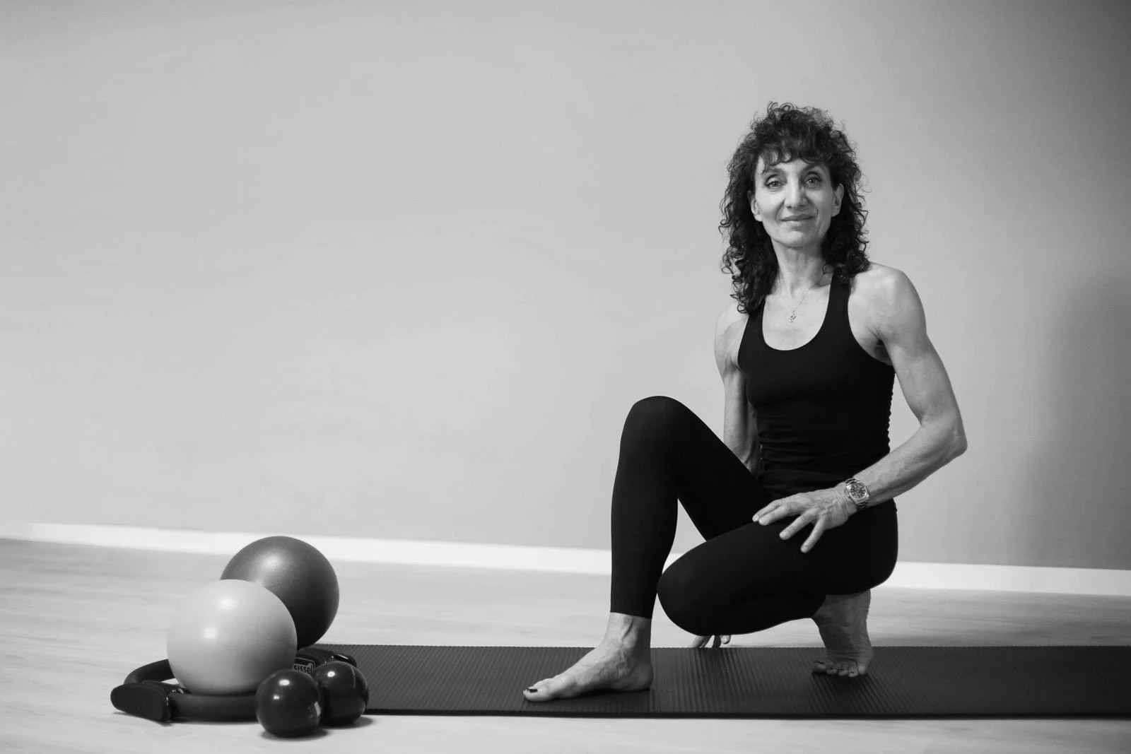 Phaedra Imbert, Pilates instructor in Lugano, seated on a mat beside Pilates props in her studio.