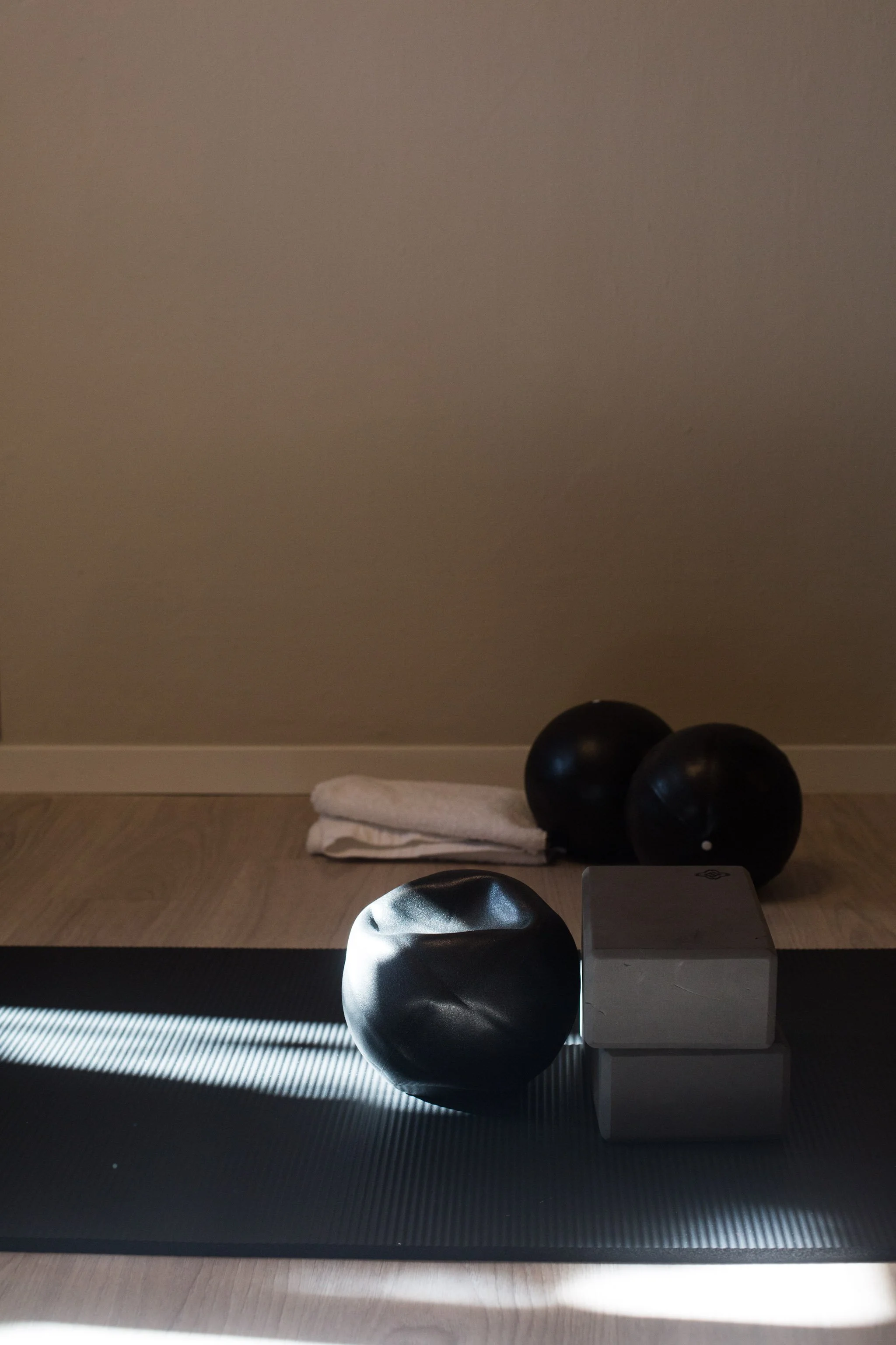 Pilates props, including exercise balls, a block and folded towels, arranged on a mat at Phaedra Pilates studio in Lugano.