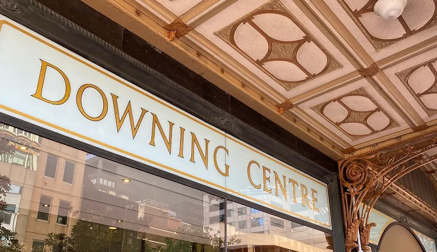 Sign reading 'Downing Centre' above glass entrance with decorative ceiling and ornate metal brackets.