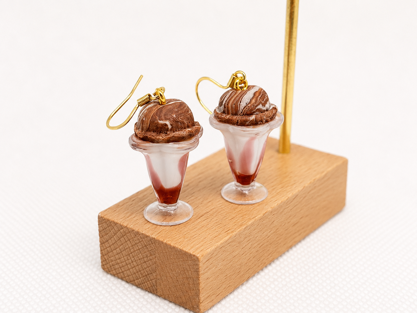 Miniature glass dessert cups earrings with chocolate and vanilla swirl soft serve ice cream, topped with chocolate sauce and ice cream scoops
